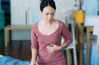 Mujer sosteniendo su estómago con expresión de dolor